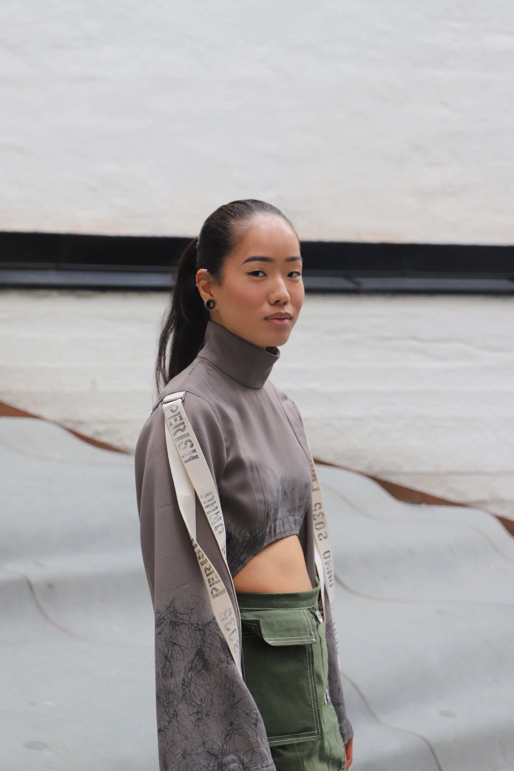 Anna wearing a grey cropped turtleneck with white straps on sleeves paired with a green skirt with cargo pocket.