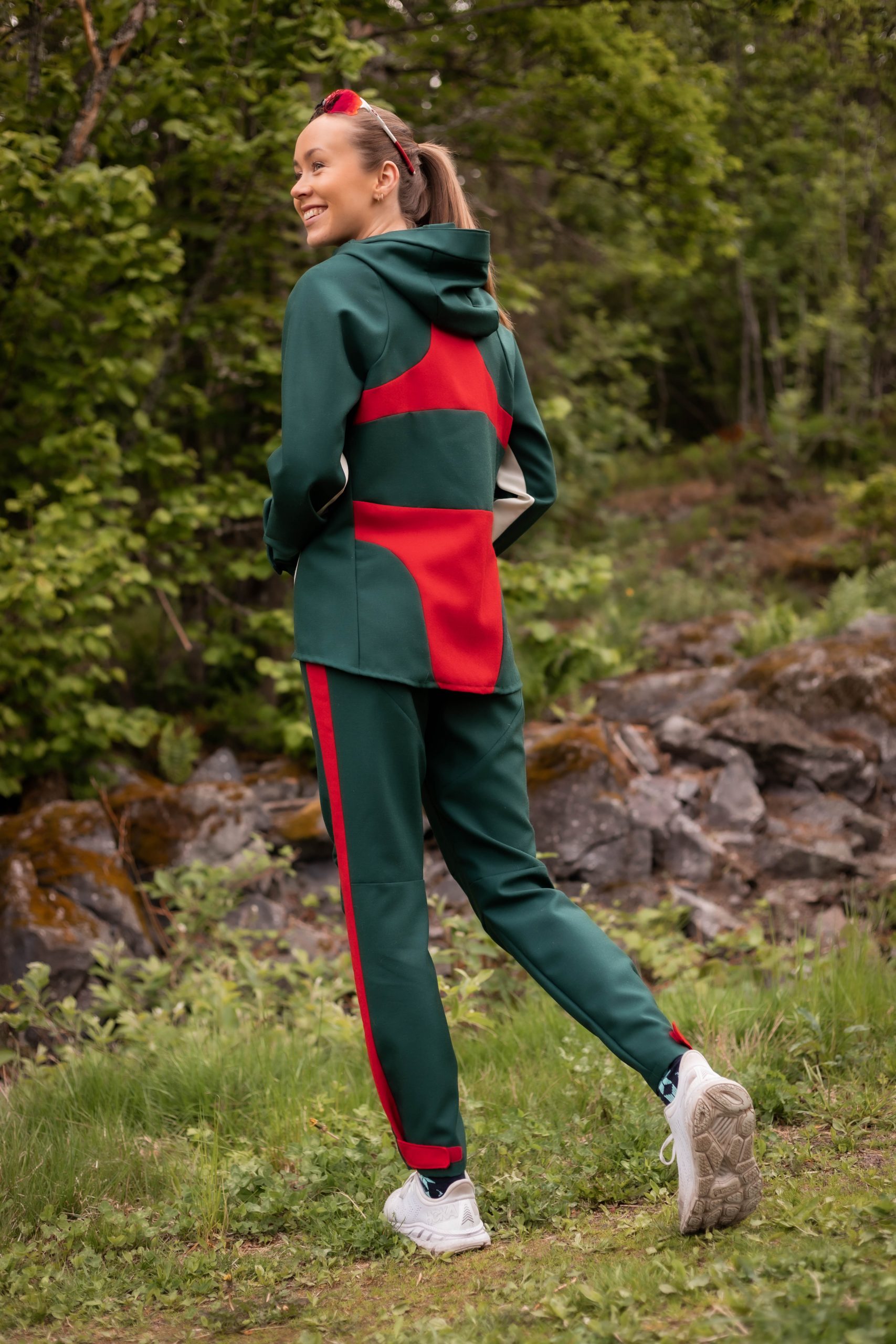 Woman wearing a green and red track suit, in the forest.