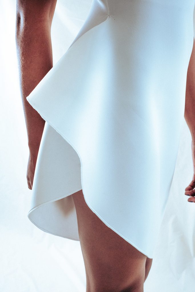 Detaljbilde av en hvit kjole kuttet i geometriske former. 